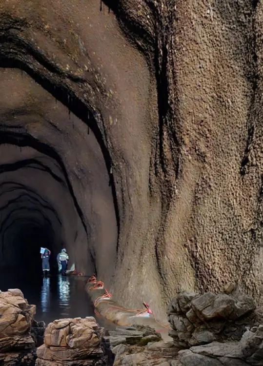 Dos profesionales inspeccionan un túnel subterráneo inundado durante un estudio geotécnico.